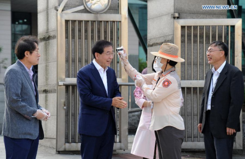 A staff worker checks the temperature of Seoul Mayor Park Won-soon (2nd L) at an elementary school in Seoul, South Korea, on June 17, 2015. South Korea on Wednesday reported eight more cases of the Middle East Respiratory Syndrome (MERS) infection and one more death, bringing the death toll to 20. (Photo/Xinhua)