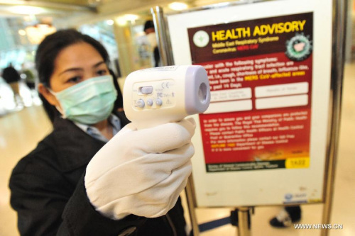 An officer holding a digital thermometer checks people's body temperature at Suvarnabhumi Airport in Bangkok, Thailand, June 21, 2015. (Photo: Xinhua/Rachen Sageamsak)