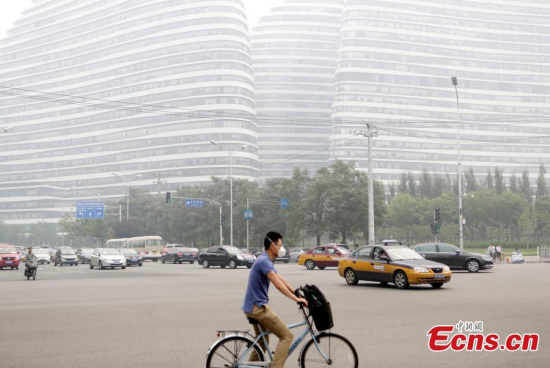 A cyclist wearing a face mask rides on a street on a smoggy day in Beijing, June 23, 2015. Beijing was hit by serious air pollution on Tuesday. (Photo: China News Service/Li Huisi)