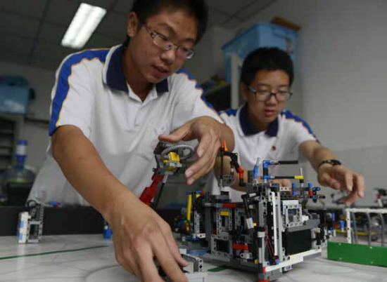 Guo Zhuoxuan (left) and Zhang Xinyu, members of a robotics club at the middle and high school affiliated with Jiaotong University in Beijing, calibrate their robot on Thursday. (Wei Xiaohao/China Daily)