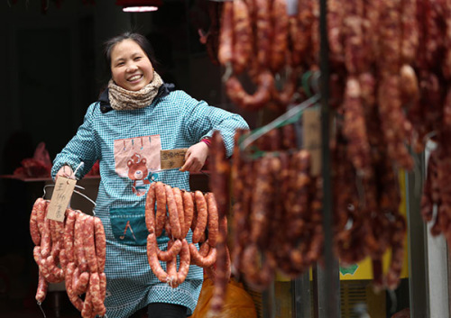 A woman in Xi'an, Shaanxi province, puts newly made sausages outside to dry them. (Photo/China Daily)