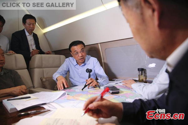 Chinese Premier Li Keqiang (C) discusses rescue plans with officials of a State Council work team on a plane flying to Hubei province on June 2, 2015. (Photo: China News Service/ Liu Zhen)