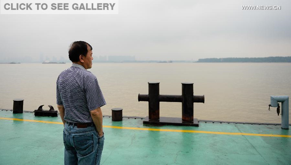 A passenger relative looks at the Yangtze River as he waits for information at the Wumadu port in Nanjing, capital of east China's Jiangsu Province, June 2, 2015. (Photo: Xinhua/Li Xiang)