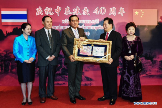 Thai Prime Minister Prayuth Chan-ocha (C) presents a set of commemorative postage stamps to Chinese Ambassador to Thailand Ning Fukui (2nd R) during a reception held by the Chinese Embassy in Thailand to mark the 40th anniversary of Sino-Thai diplomatic relations in Bangkok, Thailand, July 1, 2015. (Photo: Xinhua/Li Mangmang)