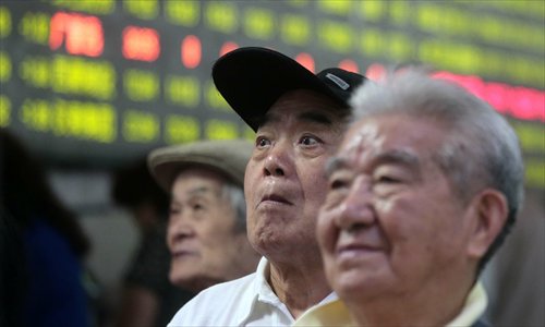 Investors nervously watch a stock trade board on Monday in Shanghai. The benchmark Shanghai Composite Index surged Monday morning following a weekend of emergency measures to shore up the slump. (Photo: Yang Hui/GT)