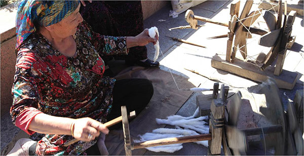 A Uygur woman revives old skills as she weaves silk using a loom as part of a restoration project at the Technological Protection Institute of the Academy of Turpan Studies. (Photo/provided to China Daily)