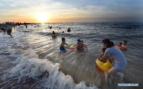 Citizens play along the beach of Haidian Island in Haikou, capital city of South China's Hainan province, July 1, 2015. A total of 12 cities and counties in Hainan witnessed high temperatures of over 37 degrees centigrade. (Photo/Xinhua)