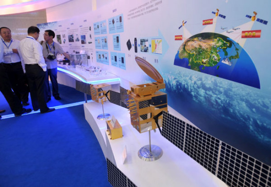 Exhibitors at Xinjiang International Exhibition Center check Beidou Navigation Satellite System terminals on Tuesday. [Photo/China Daily]