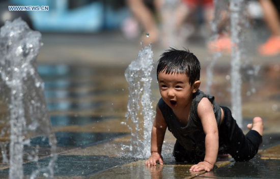 A child plays with water in Taikoo Li Sanlitun, a commercial hub in Beijing, China, July 12, 2015. An orange warning signal for possible heat wave in the next few days was issued by Beijing weather department on Sunday. (Xinhua/Chen Yehua)