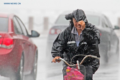 People ride in the rain in Yantai City, east China's Shandong Province, July 12, 2015. Heavy wind and rainfall appeared in Shandong due to the passing-by typhoon Chan-Hom on Sunday. (Xinhua/Tang Ke)