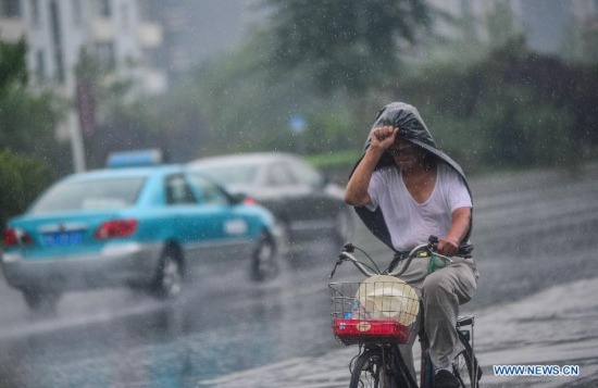 A man uses a plastic bag to shelter himself from rain on a road in Tianjin, north China, July 19, 2015. Tianjin Weather Station issued yellow alerts for rainstorm, thunder and lightning on Sunday afternoon. (Photo: Xinhua/You Sixing)