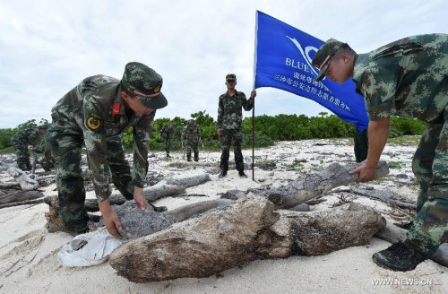 Blue Ribbon volunteers from Sansha Public Security Frontier Detachment clean up a seashore on the Yongxing island of Sansha City, south China's Hainan Province, July 17, 2015. Volunteers of Blue Ribbon Service Team cleaned up the seashores on July 17, a move to greet the third anniversary of the establishment of Sansha city. (Photo: Xinhua/Zhao Yingquan)