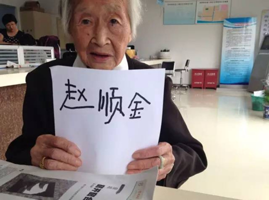 Zhao Shunjin, 100, holds up a piece of paper with her name written on it in her own handwriting at her home in Hangzhou.