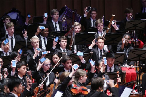 Members of the NYO-USA use their cellphones to create music while performing Tan Dun's Passacaglia: Secret of Wind and Birds. (Photo provided to China Daily)