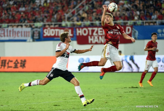 Guangzhou Evergrande's Feng Xiaoting (Top) vies with Bayern Munich's Thomas Muller during their friendly football match in Guangzhou, capital of south China's Guangdong Province, July 23, 2015. (Photo: Xinhua/Liu Dawei)