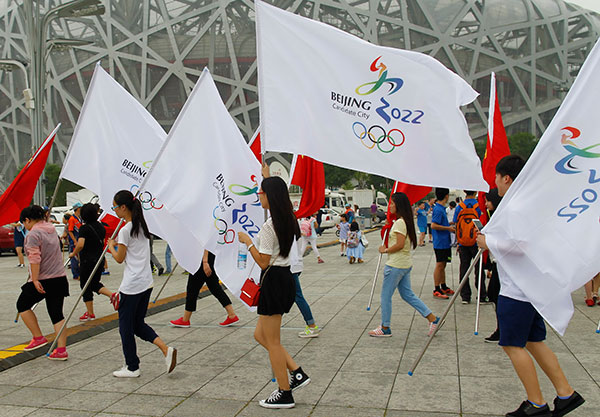 A group of volunteers walk through the square at the Bird's Nest, the landmark stadium for the 2008 Olympic Games, on Thursday, to show their support for China's bid to be the host of the 2022 Winter Olympics.(ZHU XINGXIN/CHINA DAILY)