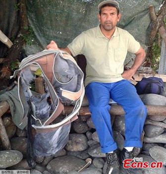 Johnny Begue, a member of a local shore cleaning association, poses on July 30, 2015 in Saint-Andre, French Indian Ocean island of La Reunion, with the remain of a suitcase found the day before on the same site where he and his fellow association members also found a two-metre (six-foot) long piece of plane wreckage that could be from the missing flight MH370. (Photo provided to China News Service)