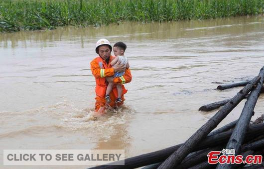 A rescuer carries a child through floodwater at a village in Wuning county, East China's Jiangxi province, July 1, 2015. More than 2,000 mu (133 hectares) of farmland and 20 buildings were submerged by the flood after heavy rain in the county. (Photo: China News Service/Jiang Dexian)