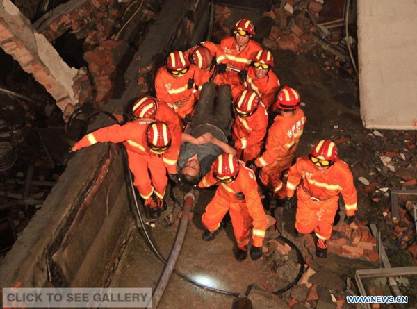Rescuers carry an injured person at a collapsed factory building in Wenling, east China's Zhejiang Province, July 4, 2015. Nine people were still trapped in the rubble of a factory building that collapsed on Saturday afternoon in east China's Zhejiang Province. (Photo/Xinhua)