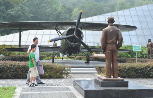 A father and son walk past statues at the Nanjing Anti-Japanese Aviation Memorial Hall. Photo by Sun Can / Xinhua