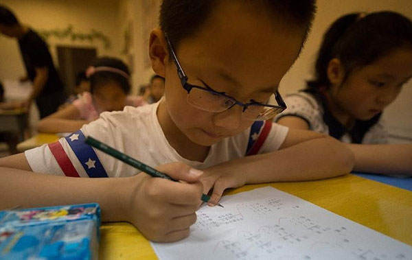 A student from a primary school in Nanjing, Jiangsu province, practices for the aoshu, or math Olympiad, during a class in July 2014.(Photo/Xinhua)