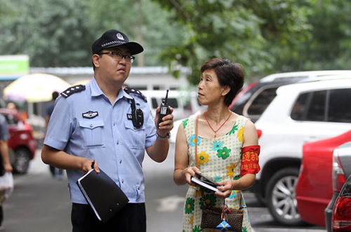 Yu Xiaohui, a resident of Beijing's Nongzhan Nanli community in Chaoyang district, tours the area with Wang Yang, a police officer. Yu is a volunteer who helps police keep a watch on the neighborhood. (Zou Hong/China Daily)