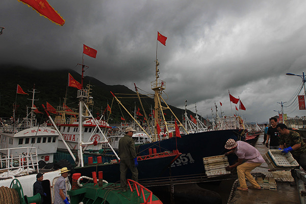 Fishermen in Wenzhou, Zhejiang province, unload their goods at a harbor on Friday as Typhoon Soudelor nears. (Photo: China Daily/Su Qiao)