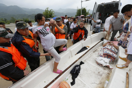 Rescuers help a pregnant woman board a boat taking her to a hospital in Ruian, Zhejiang province. Heavy rain hit the city on Sunday. (Sun Lin/China Daily)