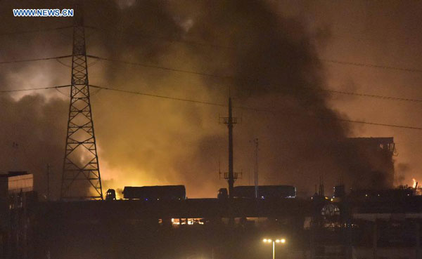 Trucks pass a bridge near the explosion site in the Binhai New Area in north China's Tianjin Municipality, Aug. 13, 2015.