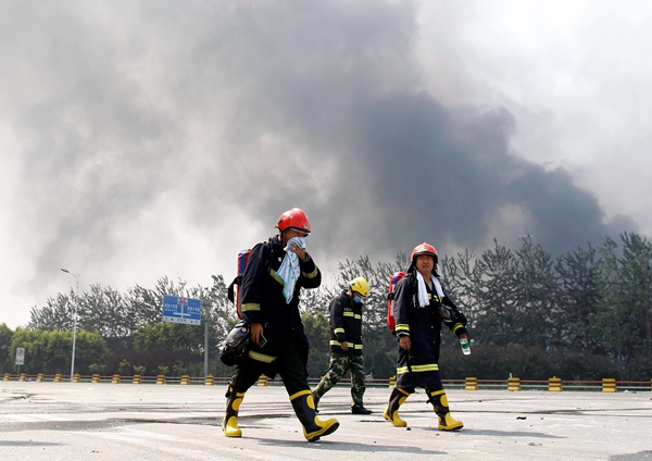 Firefighters return from the warehouse area, where they were involved in rescue operations.(ZHU XINGXIN/CHINA DAILY)