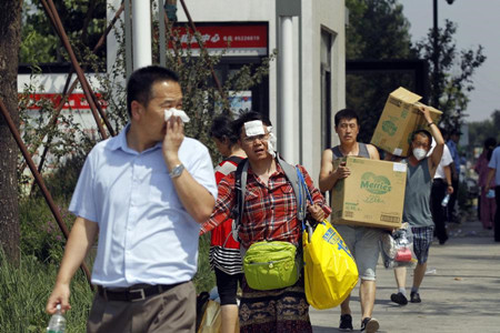 Residents near the blast site carry their baggage in an orderly evacuation in North China's Tianjin on Aug 13, 2015. (Photo: China Daily/Zhu Xingxin)