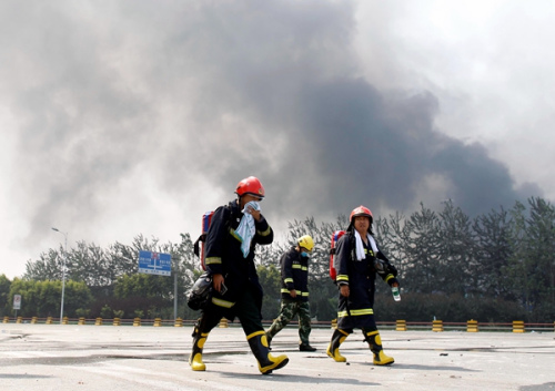 Firefighters return from the warehouse area, where they were involved in rescue operations.(China Daily/Zhu Xingxin)