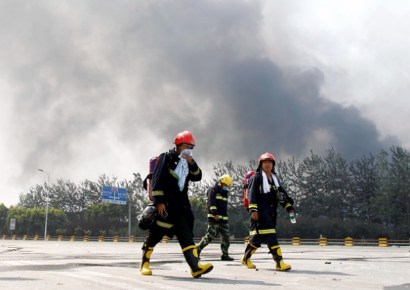 Firefighters return from the warehouse area, where they were involved in rescue operations.(Photo: China Daily / Zhu Xingxin)