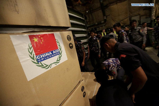 Myanmar policemen carry relief aid from a cargo plane at the Yangon International Airport in Yangon, Myanmar, Aug. 15, 2015. The emergency relief aid from the Chinese government arrived at the Yangon International Airport on Saturday night to help flood victims in Myanmar. (Xinhua/U Aung)