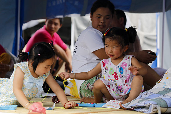 Children play at a temporary settlement at a primary school in Tianjin, Aug 14. (Photo by Zhu Xingxin/Asianewsphoto)
