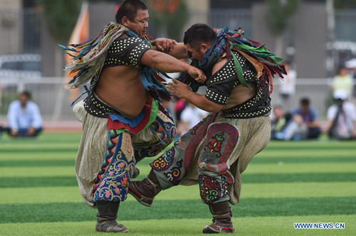 Two Mongolian wrestlers compete in men's individual event of the Mongolian wrestling, or Boke in Chinese, during the 10th National Traditional Games of Ethnic Minorities of China in Ordos, north China's Inner Mongolia Autonomous Region, Aug. 16, 2015.  (Photo: Xinhua/Ou Dongqu)