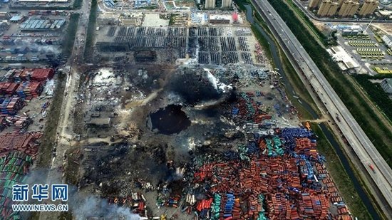 An aerial photograph taken on Aug 16, 2015 shows a huge hole at the center of the site of a series of explosions in North China’s Tianjin municipality. The hole is filled with dark water.(Photo/Xinhua)