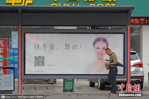 People walk past a marry me LED advertisement which has been installed at a bus station in Xiangyang, Central China's Hubei province, Aug 18, 2015. (Photo/CFP)