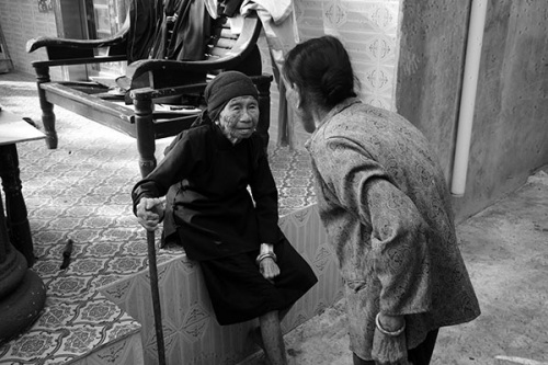 Everyday life for former comfort woman Huang Youliang, 88(left), is limited to just a few paces in front of the door at her home in Jiama village, Lingshui county, Hainan. She has had a serious rheumatic disease for years and cannot walk unassisted. Huang is supported in her will to live by the hope of an official apology from the Japanese government. (China Daily/Huang Yiming)