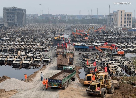 Rescuers and machines clean up burnt vehicles in the core blast area in Tianjin, north China, Aug. 20, 2015. (Xinhua/Zhang Chenlin)