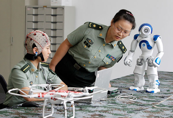 Two researchers at the PLA Information Engineering University test how to control robots with the mind.(Photo/China Daily)