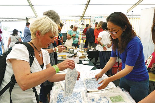 A ceramics artist from Jingdezhen shows off designs at an exhibition during the International Ceramics Festival in July at Aberystwyth on the coast of west Wales.(Photo provided to China Daily)