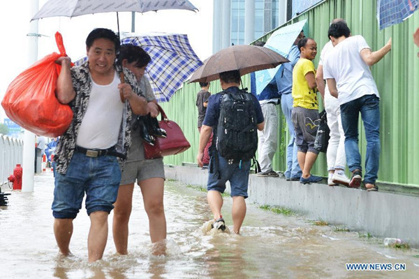 Local residents walk on a waterlogged road in rain in east China's Shanghai, Aug. 24, 2015. Shanghai witnessed gales and rainstorms since Sunday night under the influence of the approaching typhoon Swan. (Photo: Xinhua/Yuan Jing)