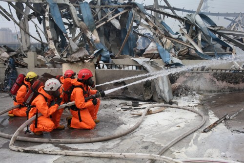 Firefighters attired in chemical protective suits work at the explosion site to extinguish fires on August 15 (XINHUA)