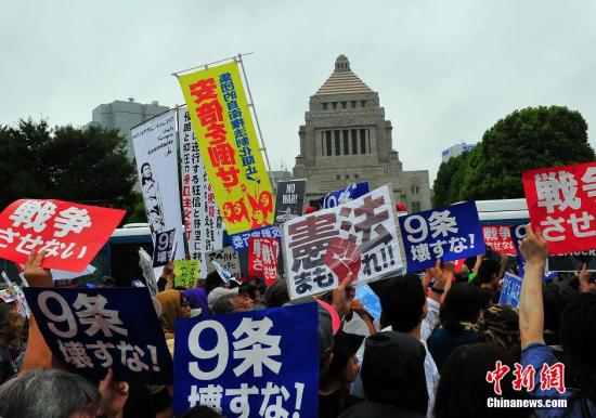 Protesters hold anti-war placards in front of the National Diet building during a rally in Tokyo, Sunday, August 30, 2015. (Photo/Wang Jian)