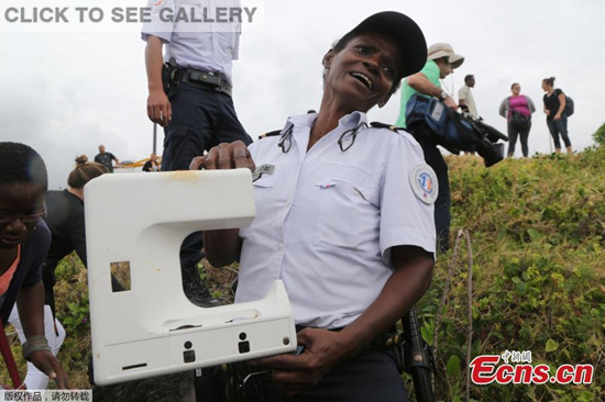 A police officer holds a piece of plastic found in Saint-Denis on Reunion Island in the Indian Ocean, Aug 4, 2015. (Photo provided to China News Service)