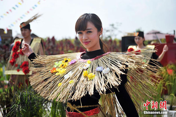 A performer in a straw dress dances in the rice fields to celebrate the festival. (Photo/Chinanews.com)