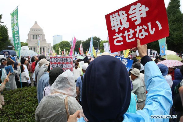 Protesters hold placards during a rally against the controversial security bills in Tokyo, Japan, Aug. 30, 2015. Some 120,000 people rallied and surrounded Japan's parliament building here on Sunday, demanding Prime Minister Shinzo Abe to rescind the controversial security bills. (Photo/Xinhua)