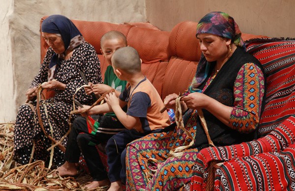 Women and children peel mulberry bark in a village in Moyu county, Hotan prefecture, Xinjiang Uygur autonomous region. (Photo by Qin Fengjing/provided to chinadaily.com.cn)