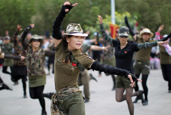 Dancers at a park in Beijing wear clothes inspired by military uniforms. Square dancers attract crowds of spectators by wearing colorful costumes and choreographing their own steps. (Photo: China Daily/Zou Hong)